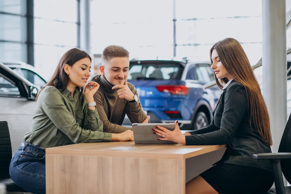 car dealer with customers in car dealership